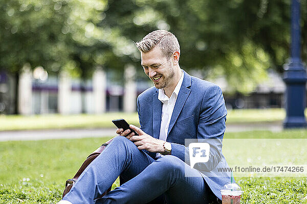 Smiling male professional using mobile phone in park