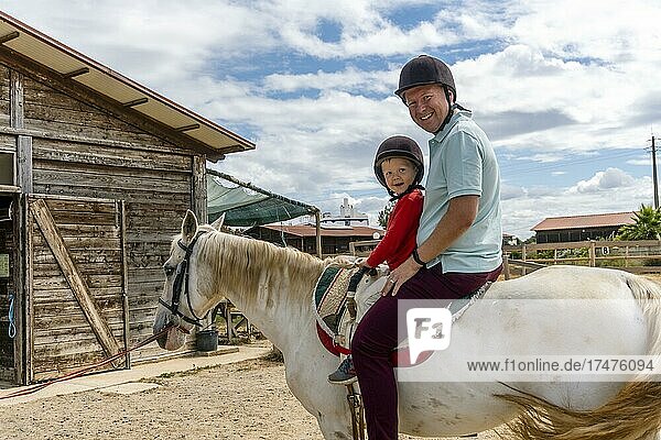 Father and son enjoying horse riding in the paddock