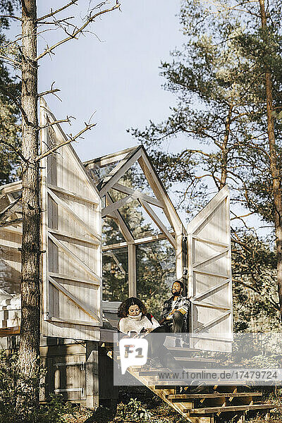 Ehepaar sitzt auf den Stufen einer Hütte im Wald