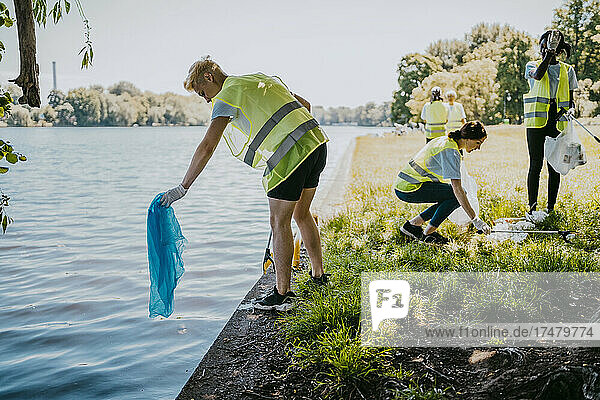 Männliche und weibliche Umweltschützer bei der freiwilligen Reinigung von Plastik am Seeufer