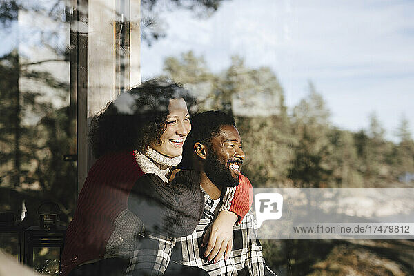 Lächelndes  wegschauendes Paar durch ein Fenster gesehen