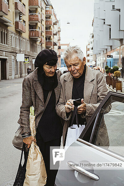 Älteres Paar benutzt Smartphone im Auto auf der Straße in der Stadt