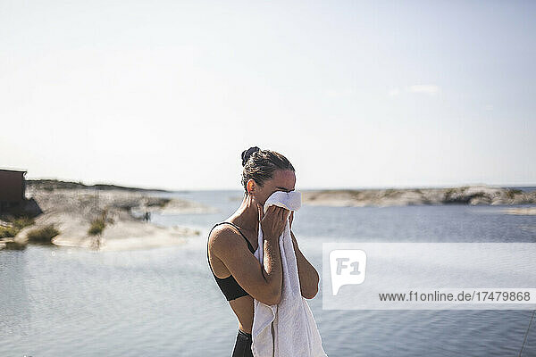Frau reinigt Gesicht mit Handtuch gegen das Meer