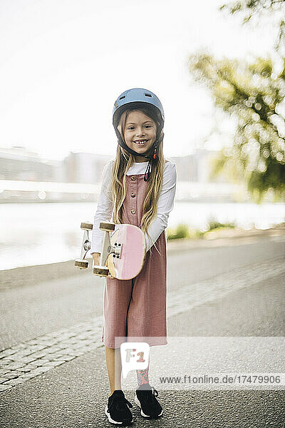 Smiling amputee girl with skateboard in park