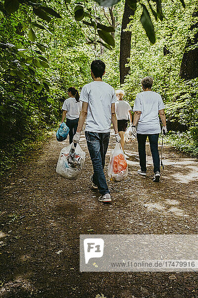 Rückansicht von weiblichen und männlichen Freiwilligen mit Plastikmüll im Park