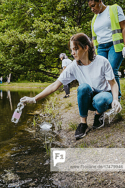 Junge Umweltschützerinnen beim Aufsammeln von Plastikflaschen aus einem Teich