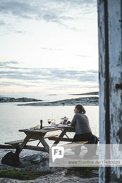 Woman having food at table during sunset