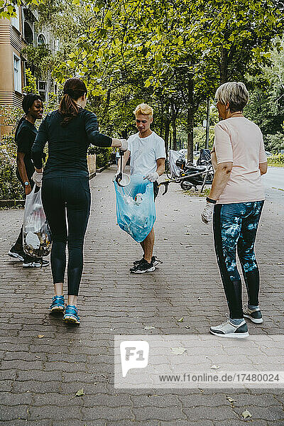 Weibliche und männliche Freiwillige sammeln Plastikmüll auf dem Fußweg auf
