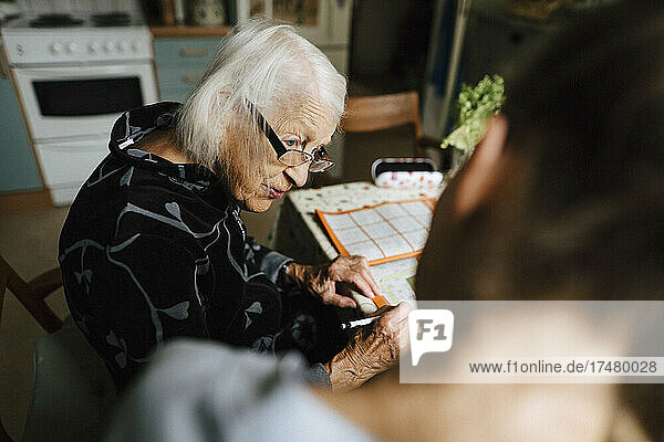 Ältere Frau im Gespräch mit einer Mitarbeiterin des Gesundheitswesens in der Küche zu Hause