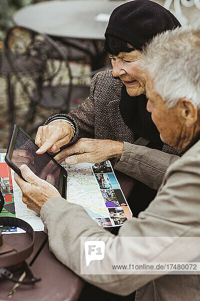 Älterer Mann und Frau nutzen GPS-Navigation über ein digitales Tablet am Tisch