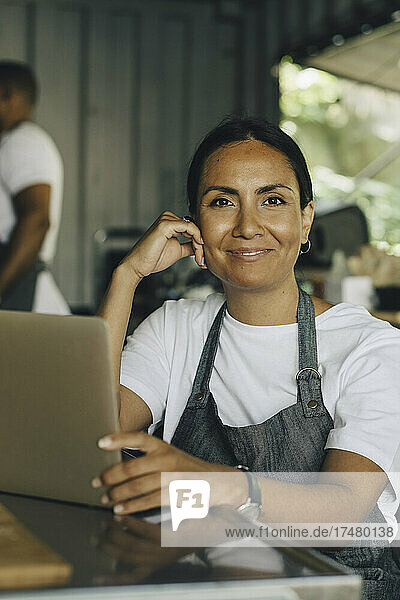 Portrait of smiling female seller with laptop in food truck