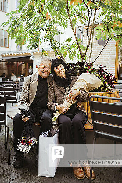 Porträt eines lächelnden Paares auf einer Bank in der Stadt im Urlaub