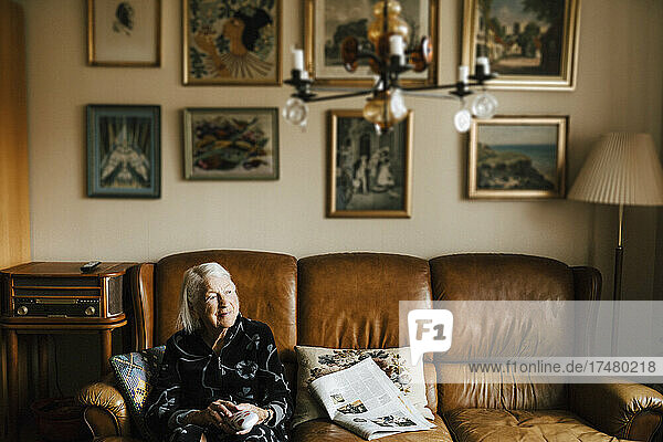 Ältere Frau  die darüber nachdenkt  auf dem Sofa im Wohnzimmer zu Hause zu sitzen