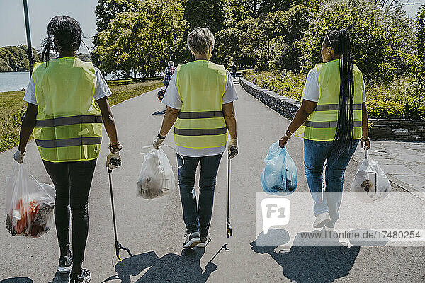 Rückansicht von Umweltschützerinnen mit Plastiktüten auf der Straße
