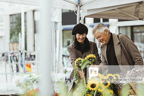 Lächelndes älteres Paar bei der Auswahl von Sonnenblumen auf dem Markt