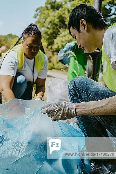 Männlicher Umweltschützer sammelt Plastik mit einer freiwilligen Helferin ein