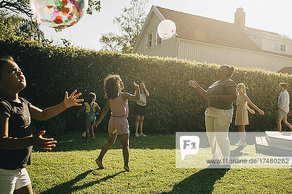 Frau und Kinder spielen mit Luftballons im Hinterhof an einem sonnigen Tag