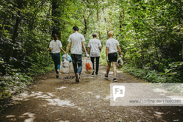 Weibliche und männliche Freiwillige gehen mit Plastikmüll im Park spazieren