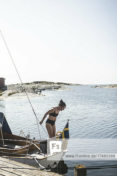 Mittlere erwachsene Frau im Bikini auf einem Segelboot an einem sonnigen Tag