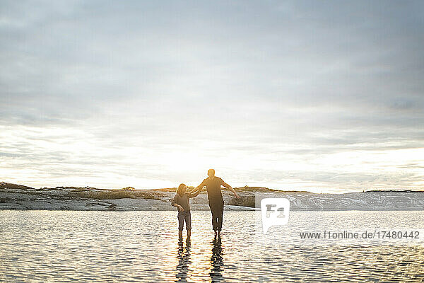 Paar steht im Meer gegen den Himmel bei Sonnenuntergang