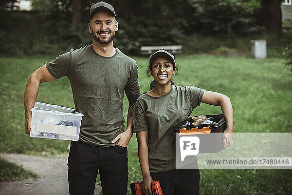 Porträt eines glücklichen männlichen und weiblichen Technikers mit Werkzeugkisten im Hinterhof