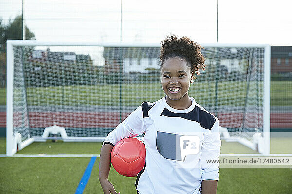 UK  Portrait of smiling female soccer player (12-13) in front of goal