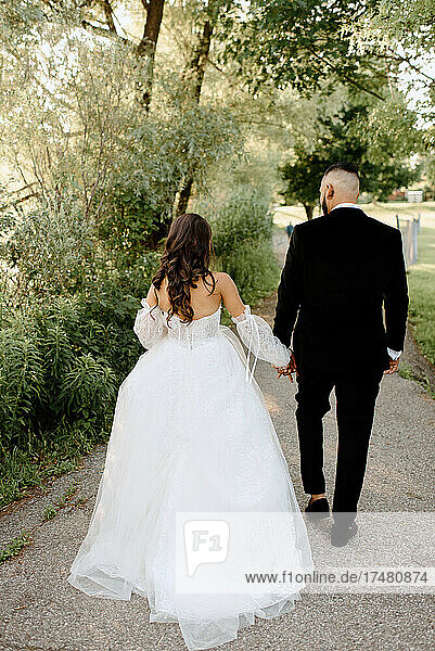 Rear view of bride and groom walking in park