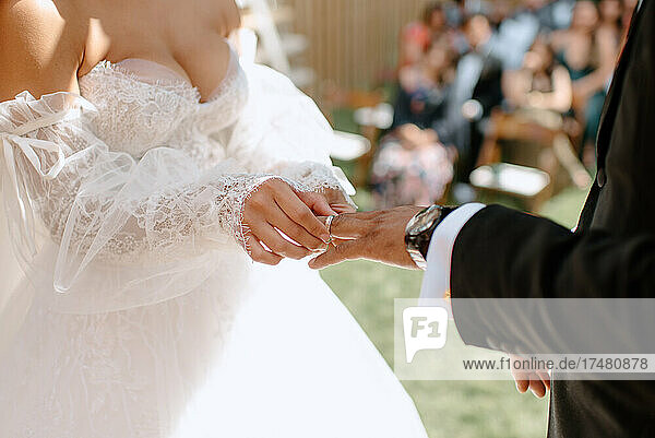 Close-up of bride putting wedding ring on grooms finger