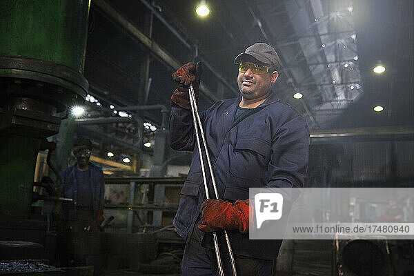 Forge worker primed for action with a set of industrial tongs