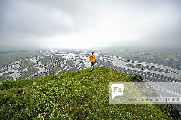 Hiker on a hill  view over alluvial land  river meandering  Dímonarhellir  Suðurland  Iceland  Europe