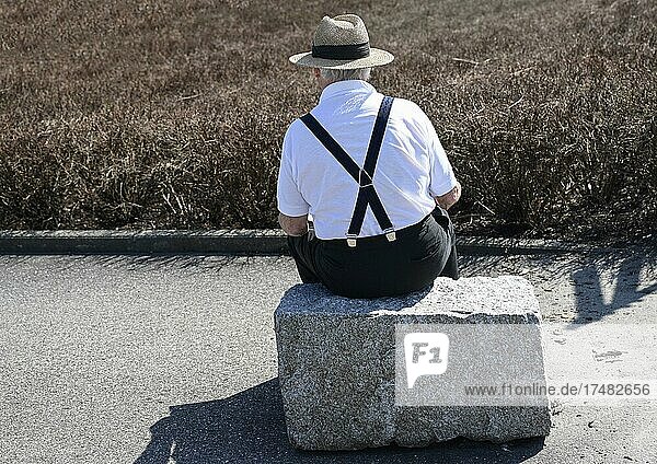 Senior sitzt auf einem Stein
