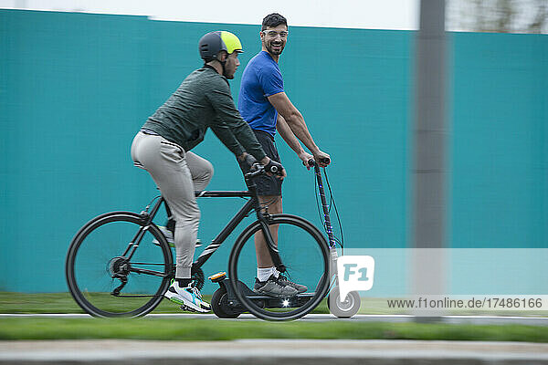 Männer fahren Fahrrad und Roller auf dem Bürgersteig