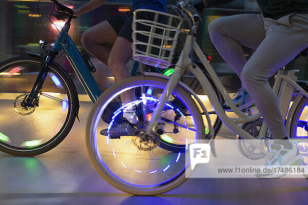 Männer fahren nachts mit beleuchteten Fahrrädern auf dem Bürgersteig