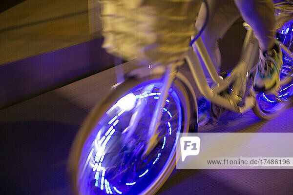 Mann fährt Fahrrad mit lila Lichtern bei Nacht