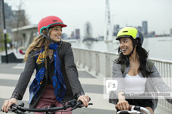 Glückliche junge Frauen Freunde in Helmen fahren Fahrräder in der Stadt
