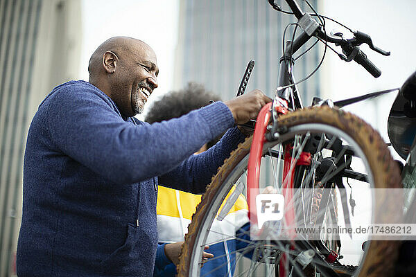 Glücklicher Mann  der sein Fahrrad auf den Fahrradträger eines Autos in der Stadt stellt.