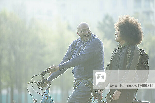 Glücklicher Vater und Teenager-Sohn auf Fahrrädern im Park