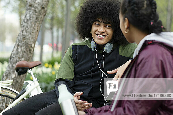 Junger Mann mit Afro im Gespräch mit einem Freund im Park