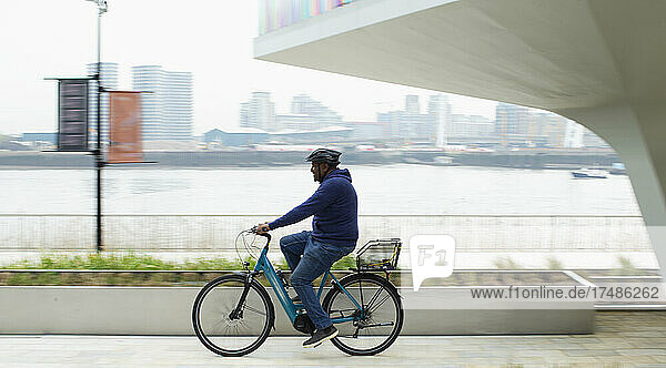 Man riding bicycle along city waterfront
