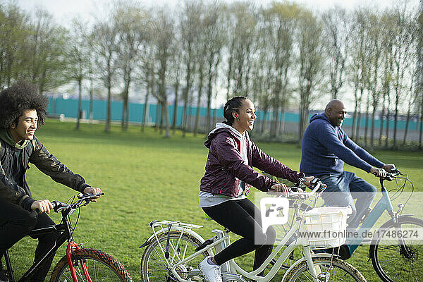 Happy family riding bicycles in park grass