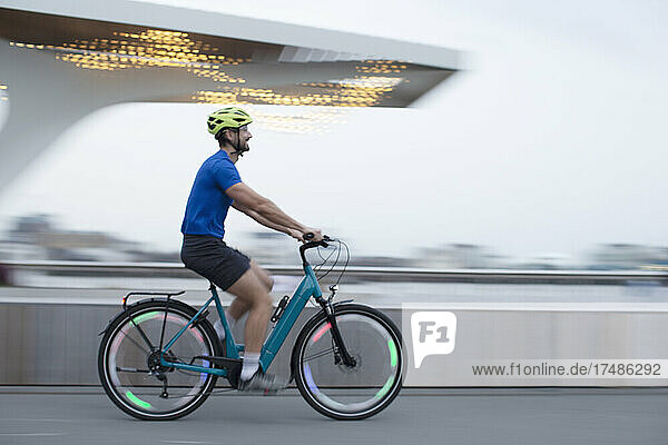 Mann fährt beleuchtetes Fahrrad in der Stadt