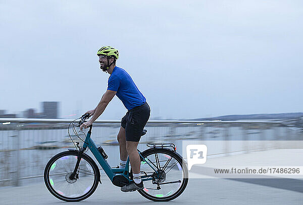 Mann fährt mit dem Fahrrad entlang der städtischen Uferpromenade