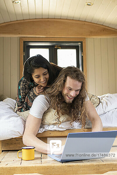 Glückliches junges Paar benutzt Laptop in kleiner Hütte