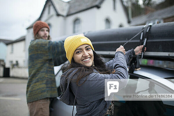Porträt glückliches junges Paar  das sein Kanu auf dem Autodach befestigt