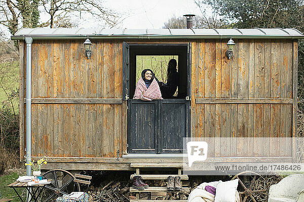 Unbekümmerte junge Frau in winzigem Hüttenvermietungsfenster