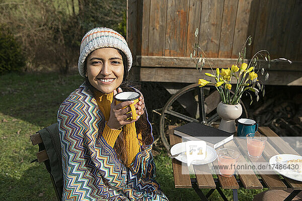 Porträt einer glücklichen jungen Frau beim Frühstück auf dem Campingplatz