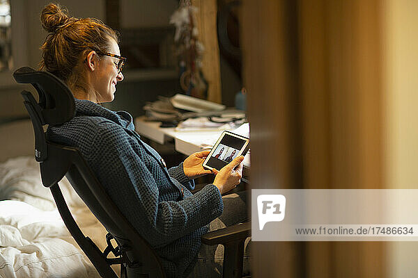 Frau  die von zu Hause aus per Videochat mit Kollegen auf einem digitalen Tablet arbeitet
