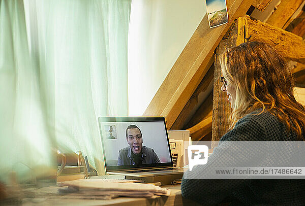 Frau bei Videokonferenz mit Kollege auf Laptop-Bildschirm zu Hause