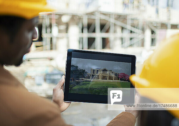 Engineers looking at digital rendering on tablet at construction site