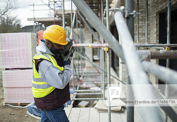 Männlicher Bauarbeiter trägt Ausrüstung auf der Baustelle